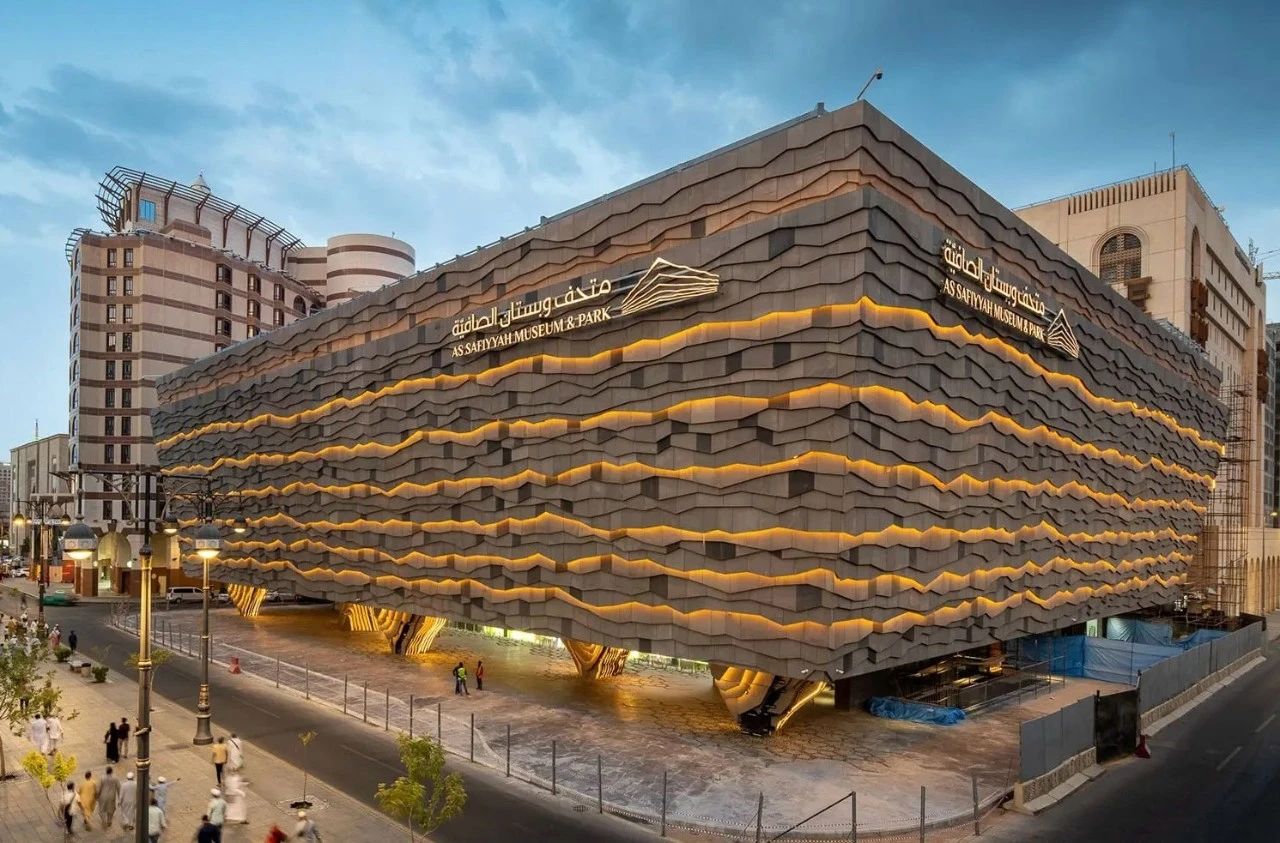 Irregular glass facade with balanced LED wall washer lighting, reflecting soft light and urban skyline at dusk.