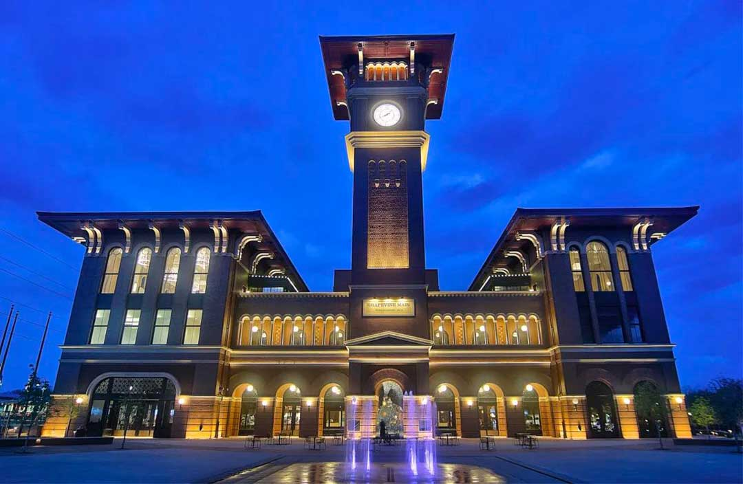 Historic clocktower above a station, warmly lit against a deep blue evening sky — façade uplighting, heritage façade lighting, architectural lighting, LED accent lighting, exterior lighting design