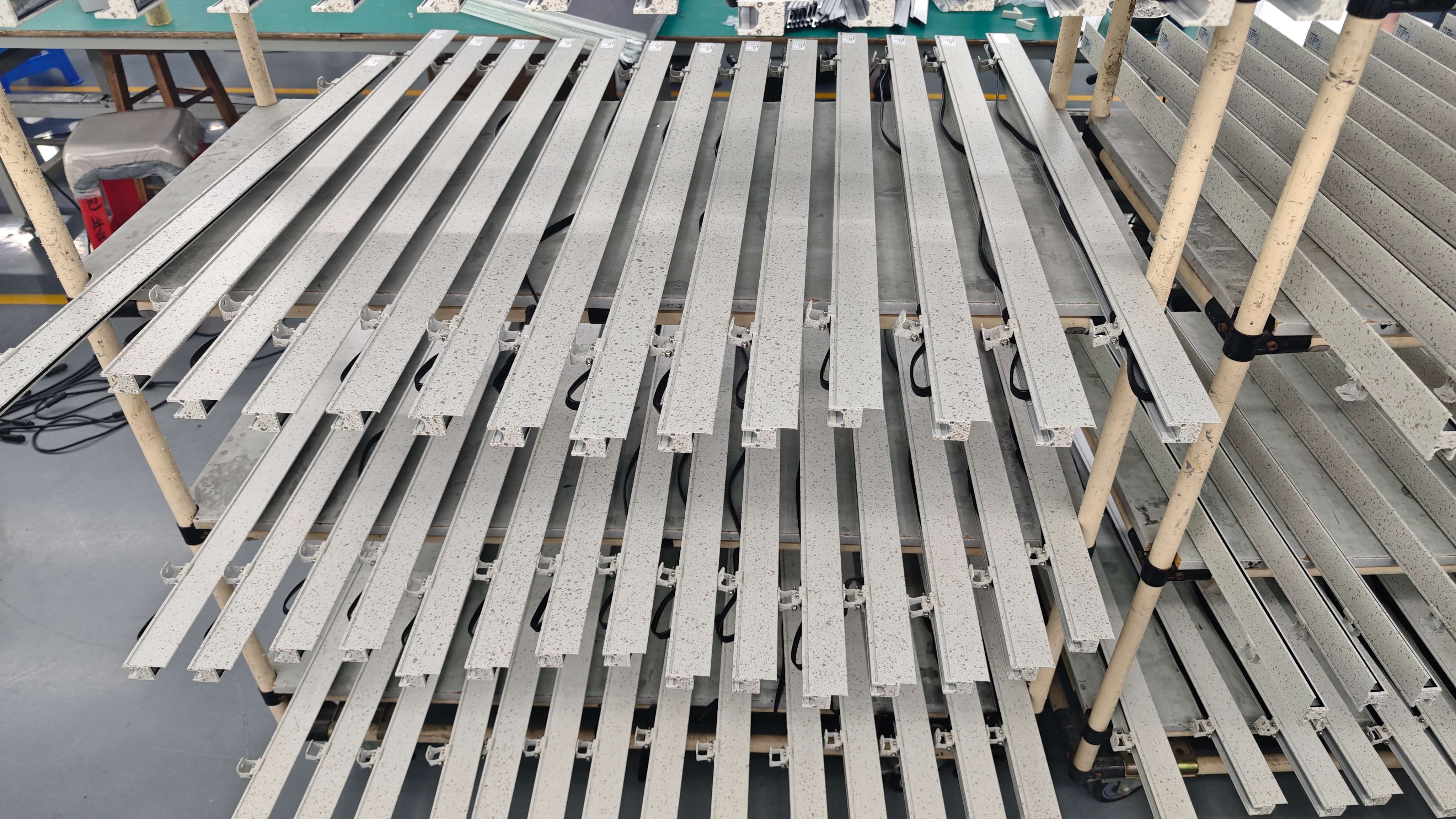Production rack with multiple custom marble-finish linear lights staged for QC and assembly
