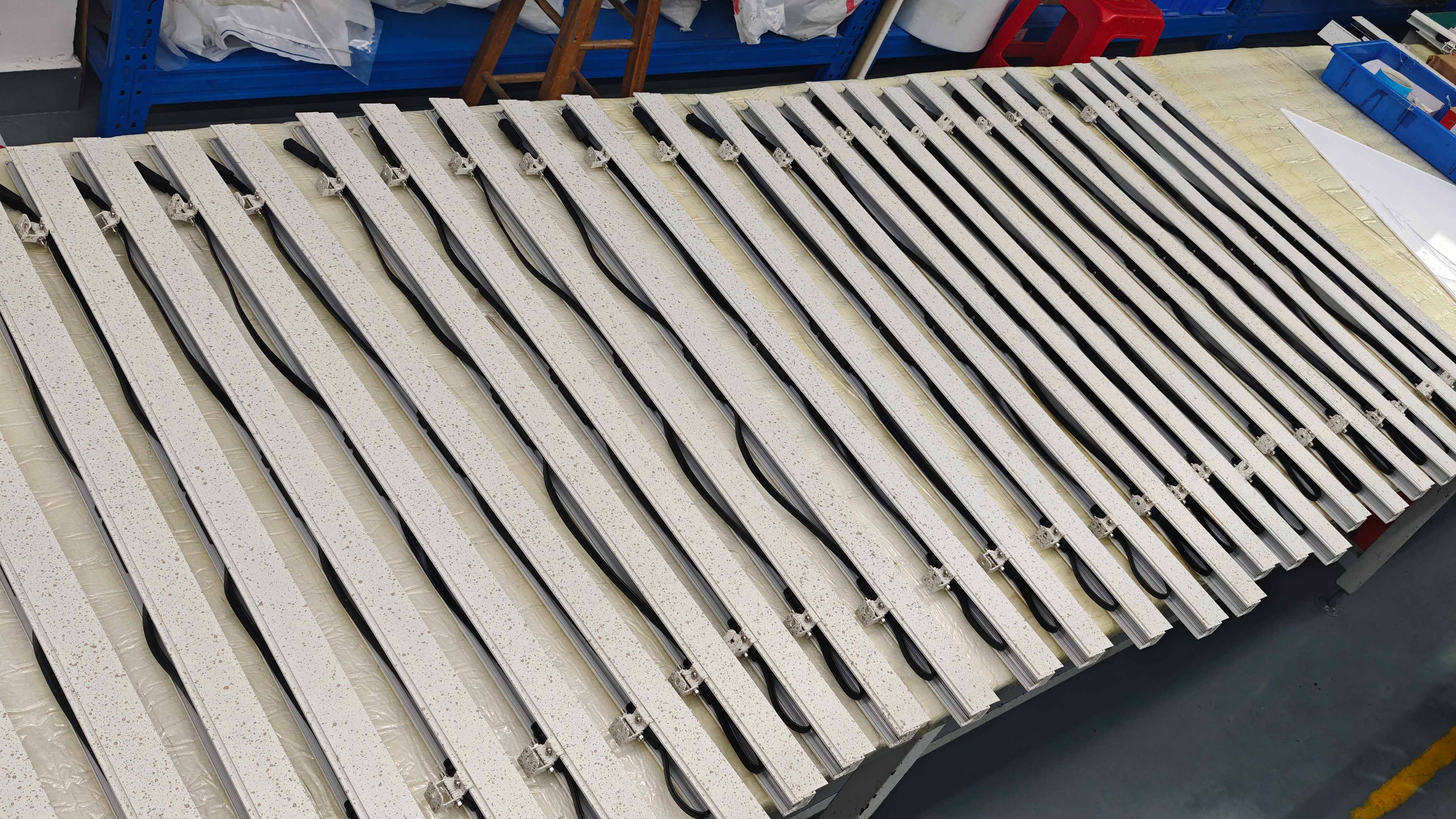 Assembled linear fixtures with pre-installed power and DMX cables and adjustable mounting brackets ready for burn-in