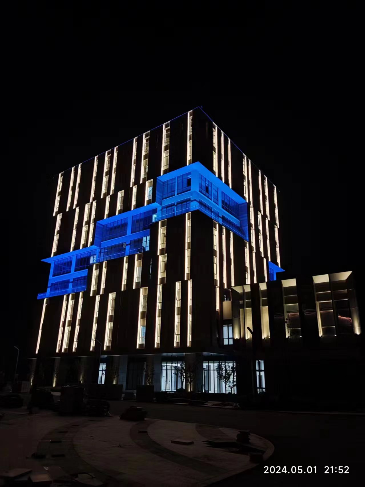 Outdoor linear LED facade lighting highlighting vertical architectural lines on a modern commercial building at night