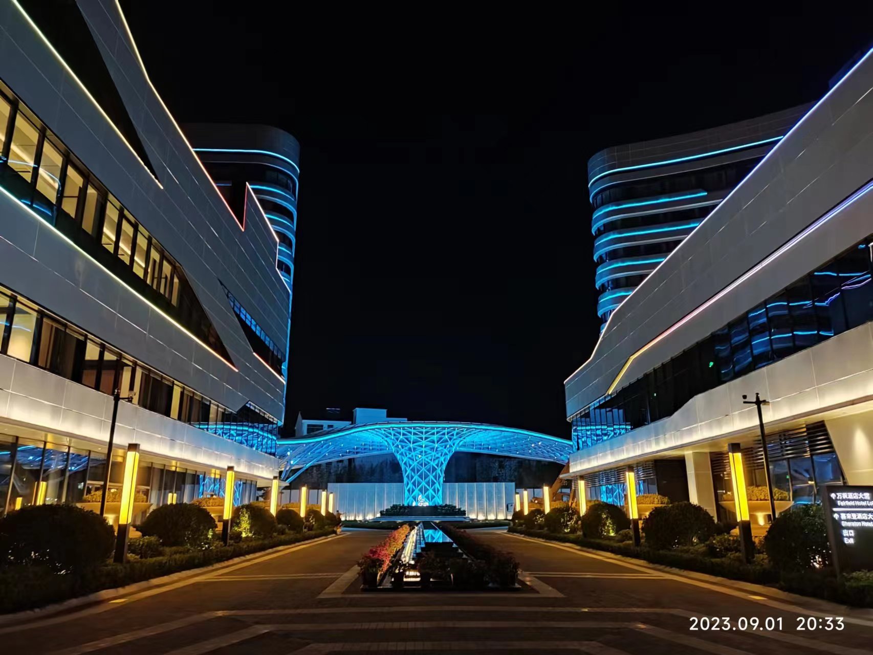 Modern commercial complex illuminated with blue architectural linear lighting and integrated landscape lighting at night