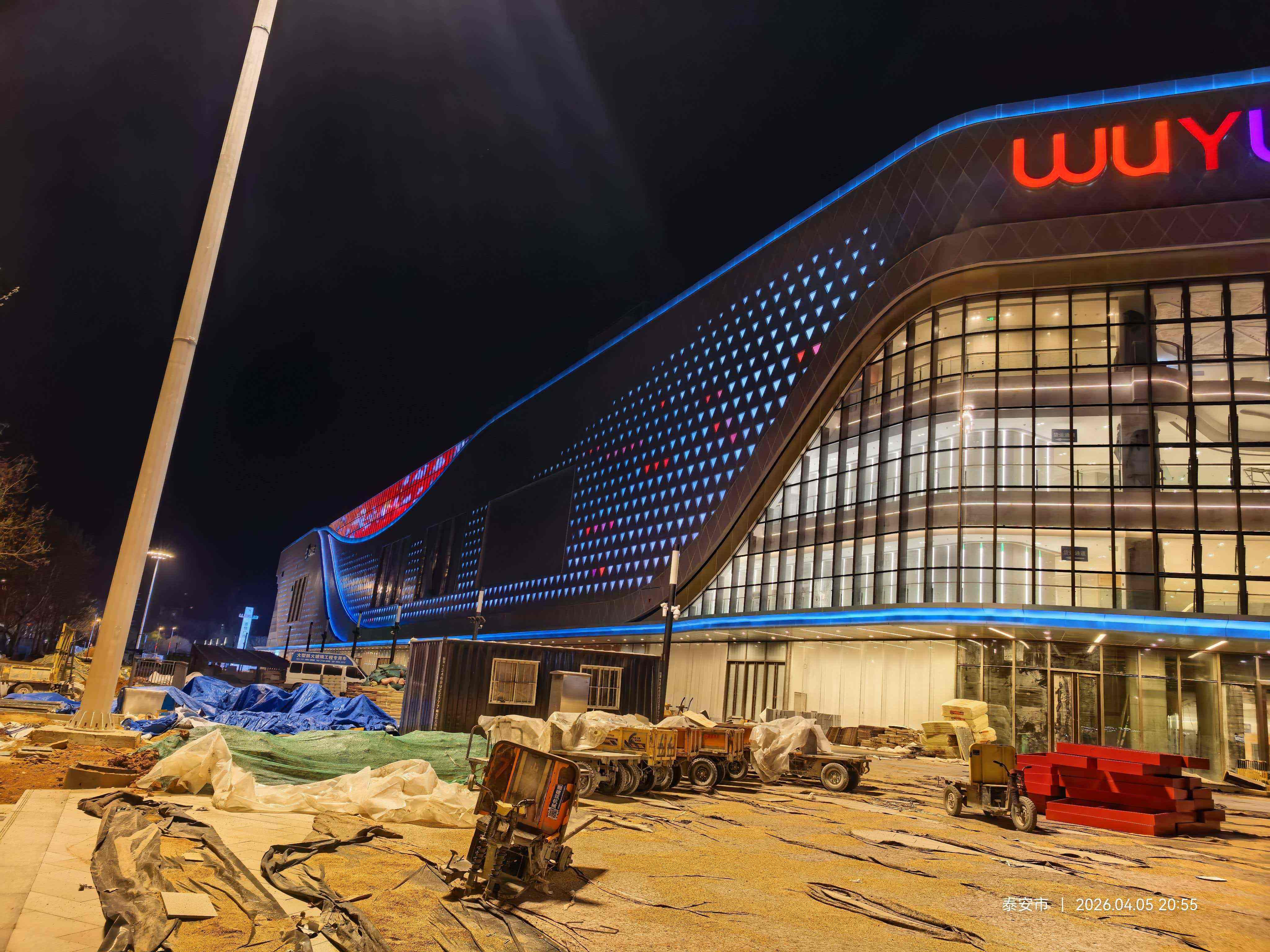 Feicheng Wuyue Plaza main entrance featuring LNJAMI colorful brand signage and architectural facade lighting at night.