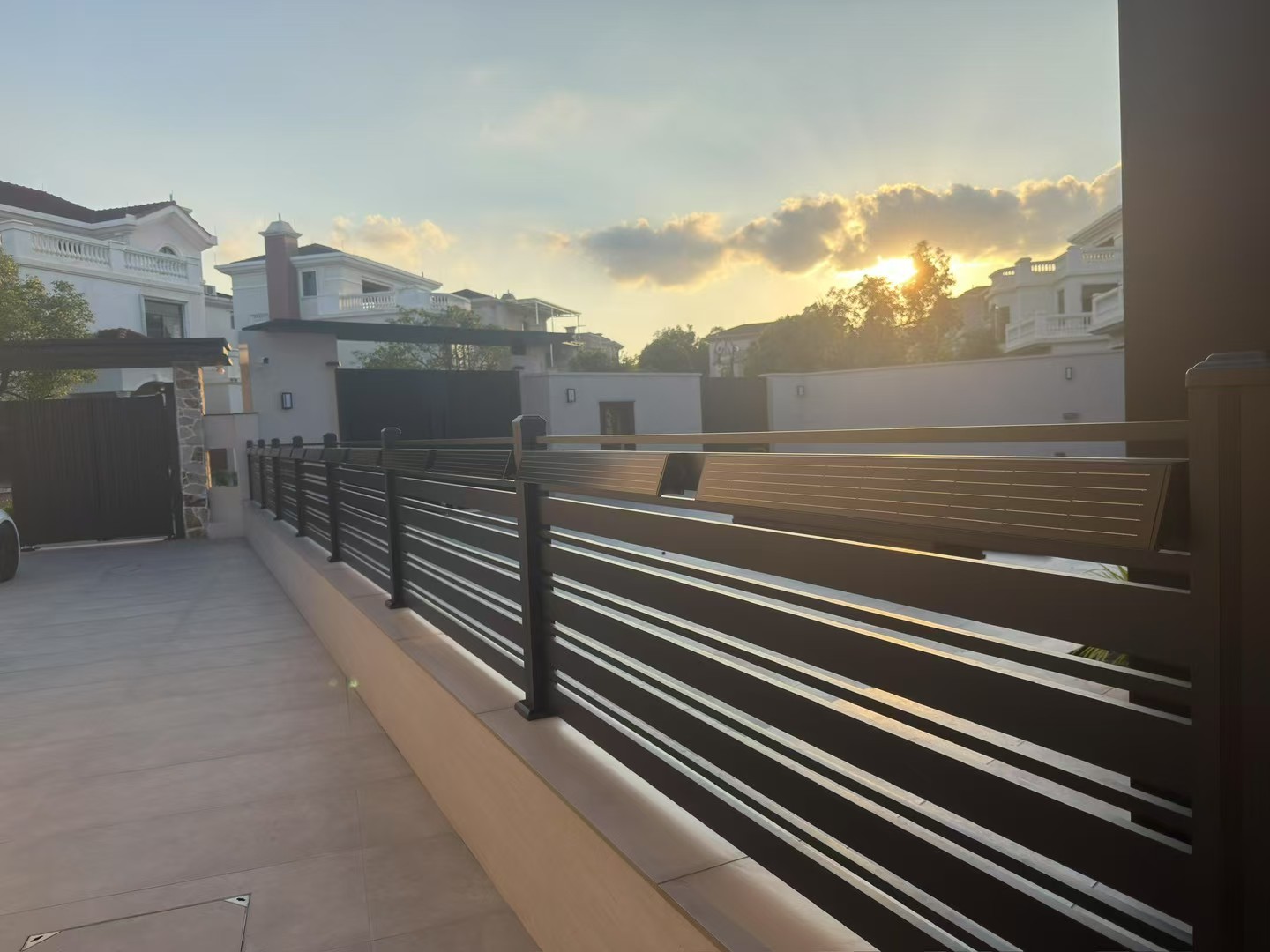 Solar wall washers installed along modern residential boundary wall during sunset for landscape architectural lighting.