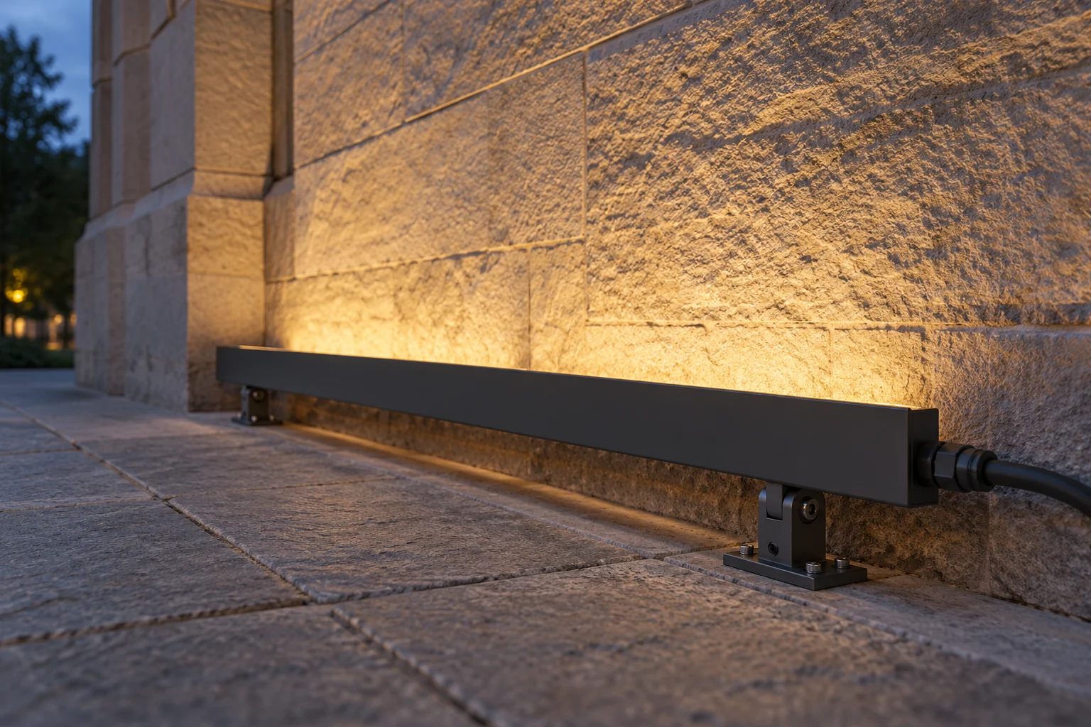 Illustrative linear wall washer with an opaque shielding edge and adjustable brackets beside a stone wall